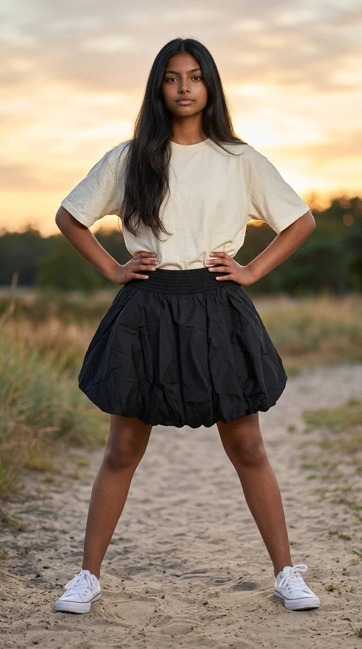 Luxury Clique black bubble mini skirt with elastic waist worn by a woman on a beach at sunset
